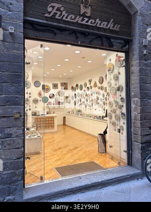 Firenzecarta. Florentine art pottery, artisanal decorative plates displayed on white walls. View from stone street, Florence, Italy. Stock Photo