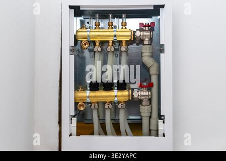 Underfloor heating system distribution board with brass manifold and pvc pipes Stock Photo