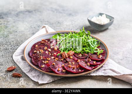 Beetroot carpaccio with walnuts and arugula salat on gray rustic background, copy space Stock Photo