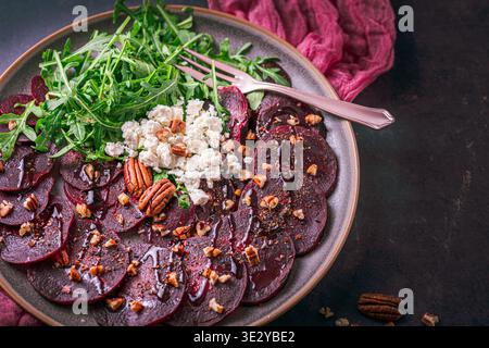 Beetroot carpaccio with balsamic glaze, walnuts, sheep cheese and rocket salat on dark background, copy space Stock Photo