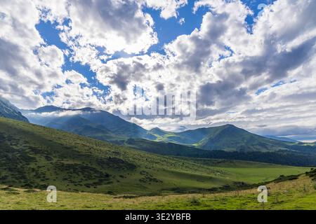 Green Pyrenees mountains and hills under a dramatic cloudy sky with sun rays shining through Stock Photo