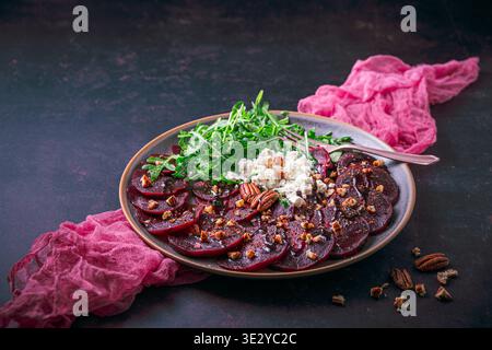 Beetroot carpaccio with balsamic glaze, walnuts, sheep cheese and rocket salat on dark background, copy space Stock Photo