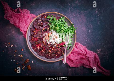Beetroot carpaccio with balsamic glaze, walnuts, sheep cheese and rocket salat on dark background, copy space, top view Stock Photo