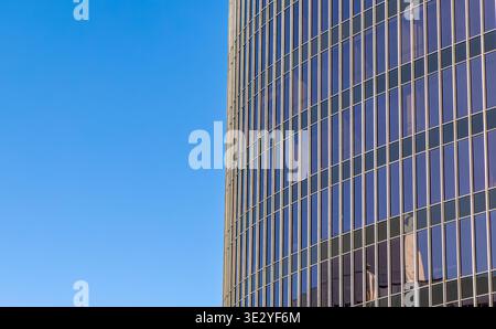 closeup image of the exterior of a modern glass skyscraper against a clear blue sky Stock Photo