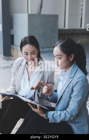 Two businesswomen are having a productive meeting in the office. They are discussing business matters, signing a contract and shaking hands Stock Photo