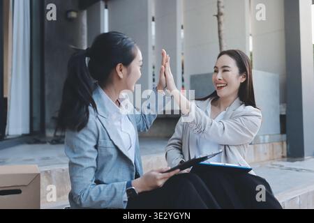 Two businesswomen are having a productive meeting in the office. They are discussing business matters, signing a contract and shaking hands Stock Photo