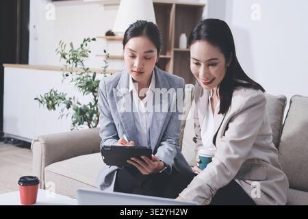 Two businesswomen are having a productive meeting in the office. They are discussing business matters, signing a contract and shaking hands Stock Photo