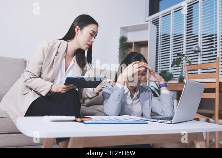 Two businesswomen feeling stressed while working on laptop in office Stock Photo
