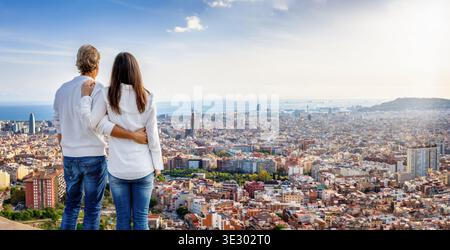 A hugging couple enjoys the panoramic view of the skyline of Barcelona, Spain Stock Photo