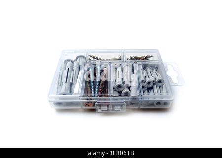 A top-down perspective of a transparent plastic partition box filled with various sizes of grey nylon wall plugs and yellow zinc-coated metal screws. Stock Photo