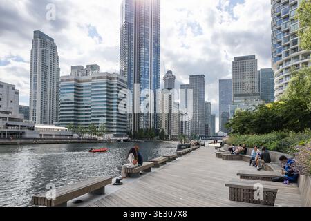People relaxing on waterfront benches at Canary Wharf. London, UK, 1 July 2023 Stock Photo