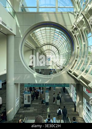 San Diego, CA - Mar 16, 2026: Attendees at TMS 2026 Meeting in San Diego Convention Center. Escalators under vaulted glass ceilings and ventilators. Stock Photo