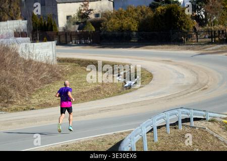 man Running on a Winding Road in a Rural Landscape outdoors Stock Photo