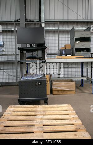 Portable workstation with computer and printer on a wheeled cart, used for inventory processing and package cubing in a warehouse. Stock Photo