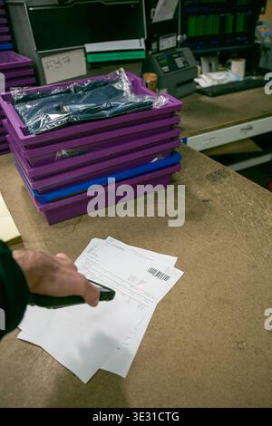 Warehouse operative using a handheld scanner to read a barcode on picking or shipping documents in an e-commerce warehouse or fulfilment centre Stock Photo