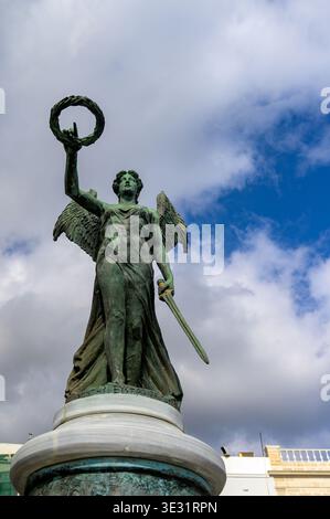 Quadriga statue with winged angel holding laurel wreath and sword on cloudy sky background Stock Photo