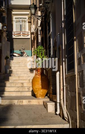 Narrow Mediterranean alleyway with terracotta amphora planter and traditional architecture in southern Europe Stock Photo