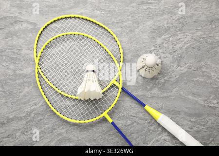Badminton rackets and shuttlecocks on grey table, top view Stock Photo