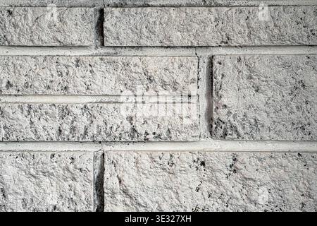 Close-up of a white painted brick wall featuring a rough, textured surface with visible mortar lines and subtle dark speckles. Stock Photo