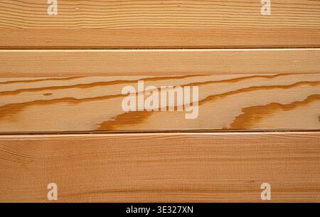 Close-up of horizontal wooden planks featuring natural grain patterns, knots, and warm honey-brown tones. Stock Photo