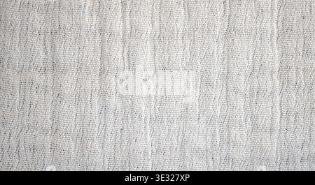 Close-up of a light-colored fabric surface featuring a subtle woven pattern with fine texture and soft neutral tones. Stock Photo