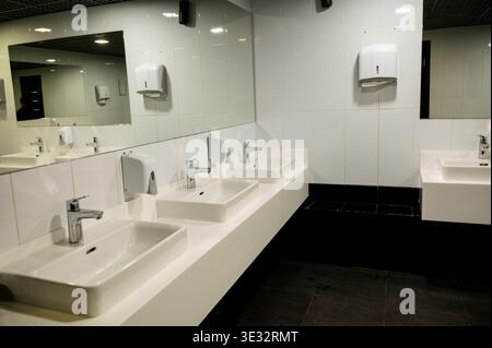 Ceramic sinks, faucet and mirrors in public restrooms. Bathroom and kitchen plumbing. Dispensers and accessories for restroom. Cleaning services. Stock Photo