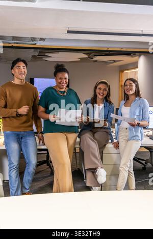 Diverse coworkers reviewing printed pages and tablet in open-plan office near wooden window Stock Photo