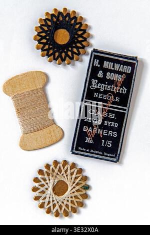 Cotton and packet of H. Milward & sons needles on white background.  Flat lay. Stock Photo