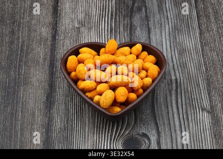 Crunchy Coated Peanuts in a Heart Shaped Bowl Isolated on White Background Stock Photo