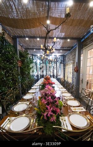 Elegant Outdoor Dining Table with Floral Centerpiece and Candle Lighting. Jewish Sukkos. Beautifully styled long dining table set for an outdoor Stock Photo