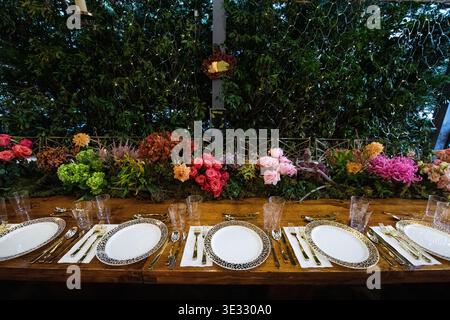 Elegant Outdoor Dining Table with Floral Centerpiece and Candle Lighting. Jewish Sukkos. Beautifully styled long dining table set for an outdoor Stock Photo