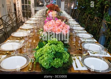 Elegant Outdoor Dining Table with Floral Centerpiece and Candle Lighting. Jewish Sukkos. Beautifully styled long dining table set for an outdoor Stock Photo