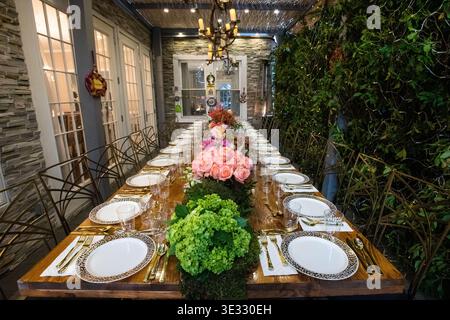 Elegant Outdoor Dining Table with Floral Centerpiece and Candle Lighting. Jewish Sukkos. Beautifully styled long dining table set for an outdoor Stock Photo