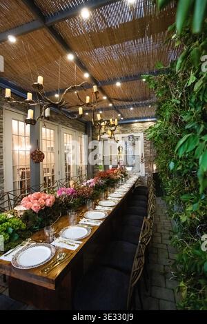Elegant Outdoor Dining Table with Floral Centerpiece and Candle Lighting. Jewish Sukkos. Beautifully styled long dining table set for an outdoor Stock Photo