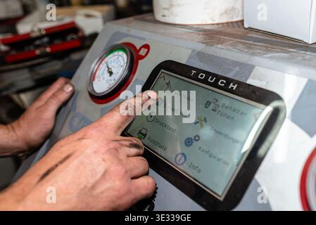 Mechanic operating an automatic car air conditioning filling machine in an auto repair garage Stock Photo