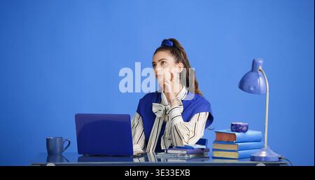 Studio, think and business woman with laptop, story inspiration or retro on blue background. Serious, author and person with computer for idea Stock Photo