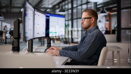 Accountant Working With Dual Screens And Expense Tracking Software In A Modern Office Setting Stock Photo