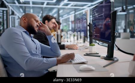 Frustrated Software Developers And Engineers Struggle With Broken Code While Working At Their Desks Stock Photo