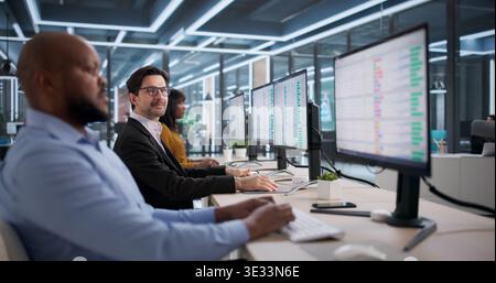 Diverse Office Team Happily Using Spreadsheets At Desks, Working Together. Young Woman Analyst Studying Reports Stock Photo