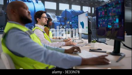 Person Using Computer And Monitoring Energy System Controls In Power Plant Room. Worker Checking Gas Pipes And Machinery Stock Photo