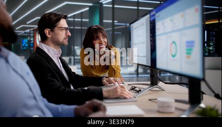 Diverse Team Of Office Workers Using Computers To Process Invoices Efficiently. The Person Could Be Coding Software Stock Photo