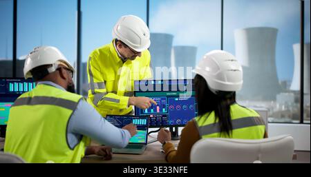 Diverse Team Of Professionals Uses SCADA Software At A Nuclear Plant. People In An Office Meet Stock Photo