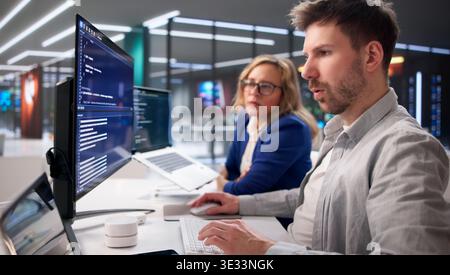 Tech Professionals Collaborating On Code In Contemporary Workspace Stock Photo
