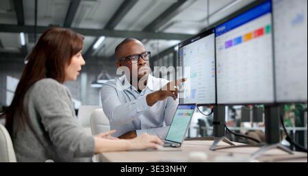 Two Young Professionals Collaborate On ERP And CRM Software, Discussing Data Analysis Stock Photo