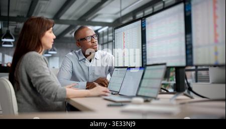 Two Professionals Collaborating On Spreadsheets And Software In Busy Office. Woman Reviewing Tax Invoices Stock Photo