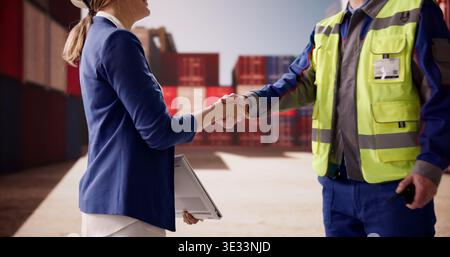 Businessman And Businesswoman Sealing Deal With Handshake At A Bustling Shipping Terminal Stock Photo