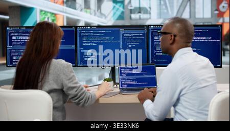 Focused Young Programmers Coding On Computers, Collaborating In Office Meeting. Agile Software Developers Analyze Data Stock Photo