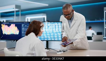 Young Scientists Working Together, Analyzing Medical Data In A Bright Lab. Two Researchers, A Man And Woman Stock Photo