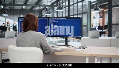 Two Software Developers Coding On Computers While An Accountant Reviews Billing Data Nearby Stock Photo