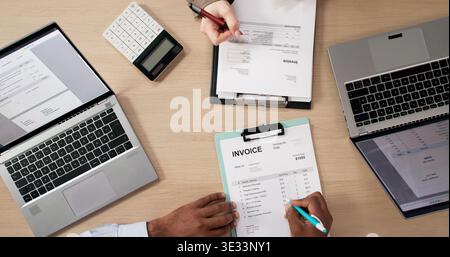 Two Young Professionals In Office Discussing Budget While Using Laptop, Calculator Nearby Stock Photo